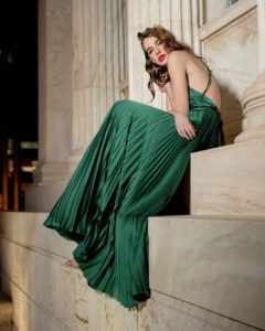 Our model in the Frances Stevens Grecian Pleated Dress, in the Emerald Green shade from the side
