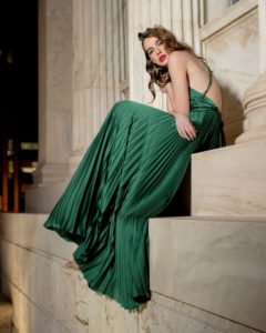 Our model in the Frances Stevens Grecian Pleated Dress, in the Emerald Green shade from the side